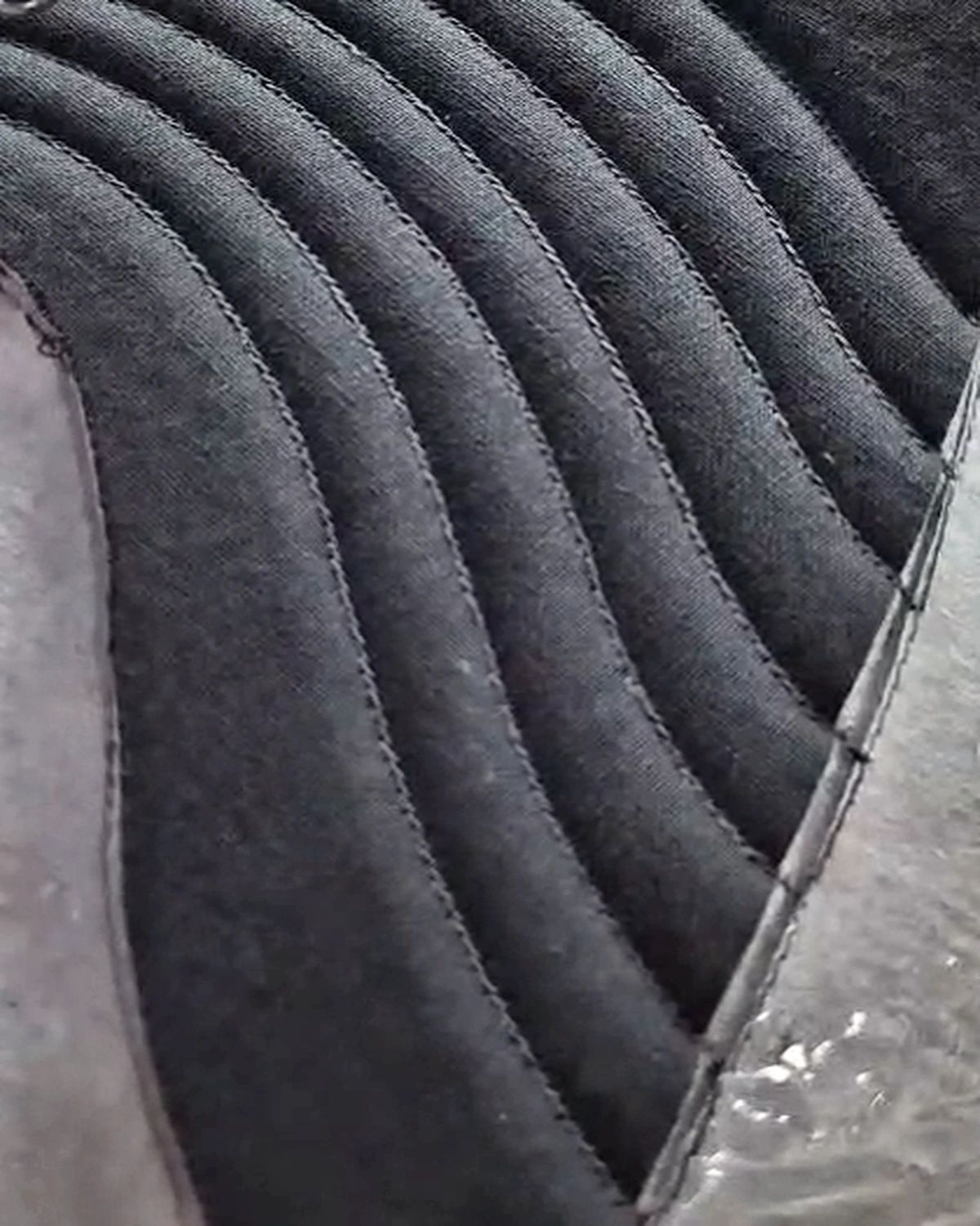 Detail: Alur jahitan relief pada kain hitam.